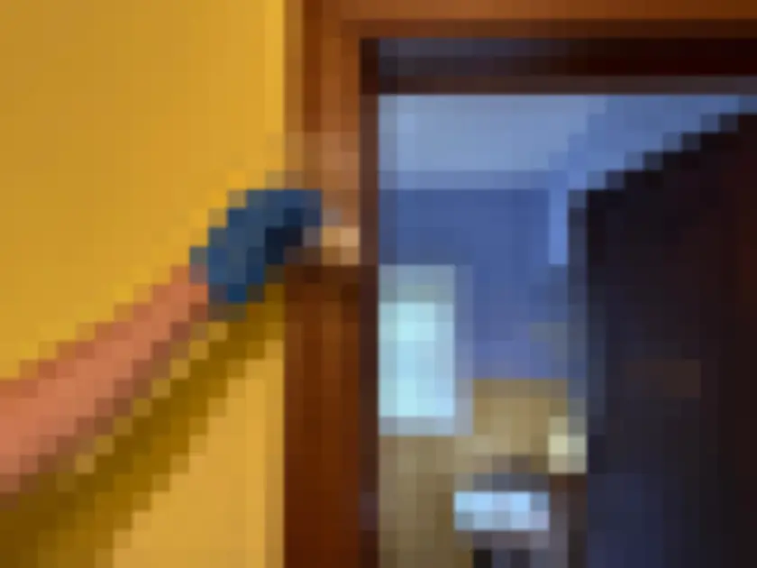 Photograph of gloved hand touches a small swab to painted door casing or trim