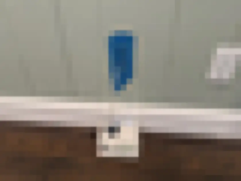 Photograph of small electric air-sampling pump with tube placed by interior painted wall